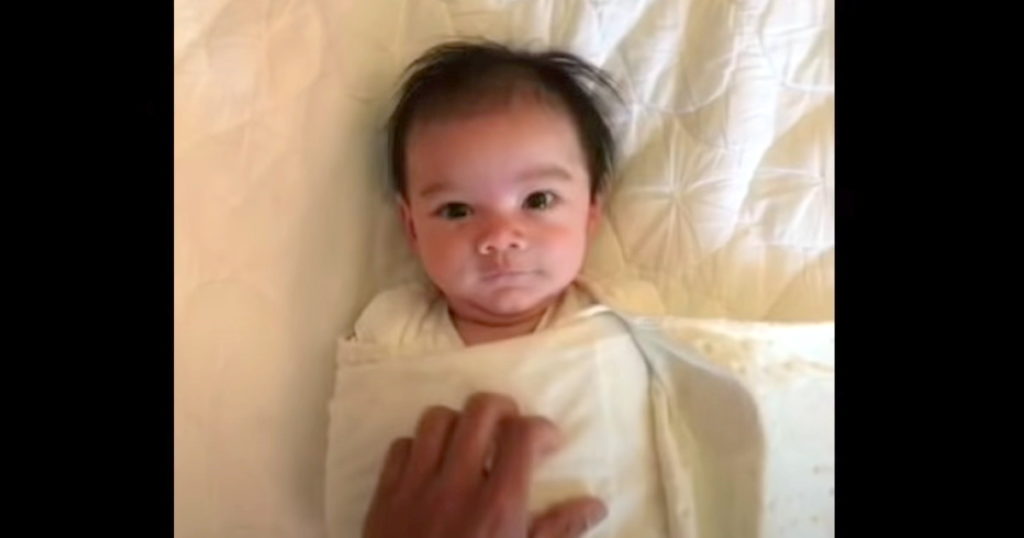Tiny baby throws arms up after being unswaddled