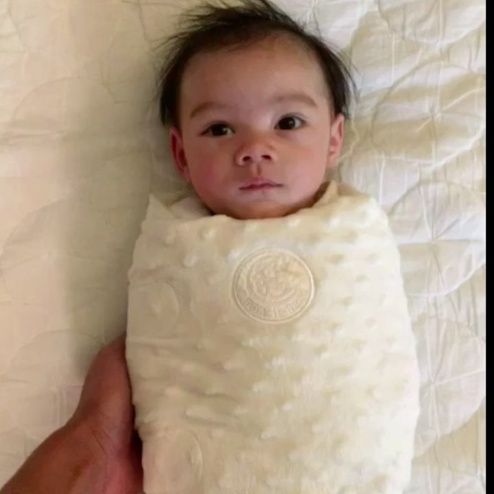 Tiny baby throws arms up after being unswaddled