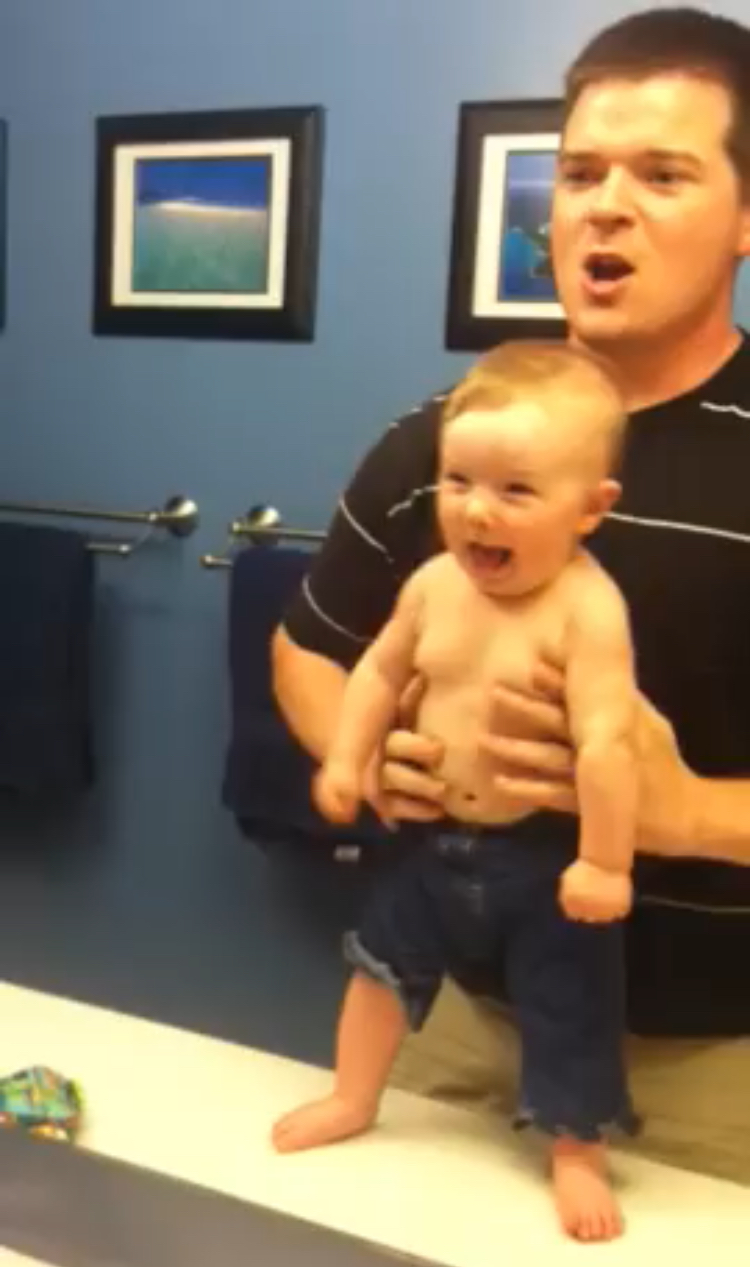 Strong baby flexes muscles making dad fall apart with laughter
