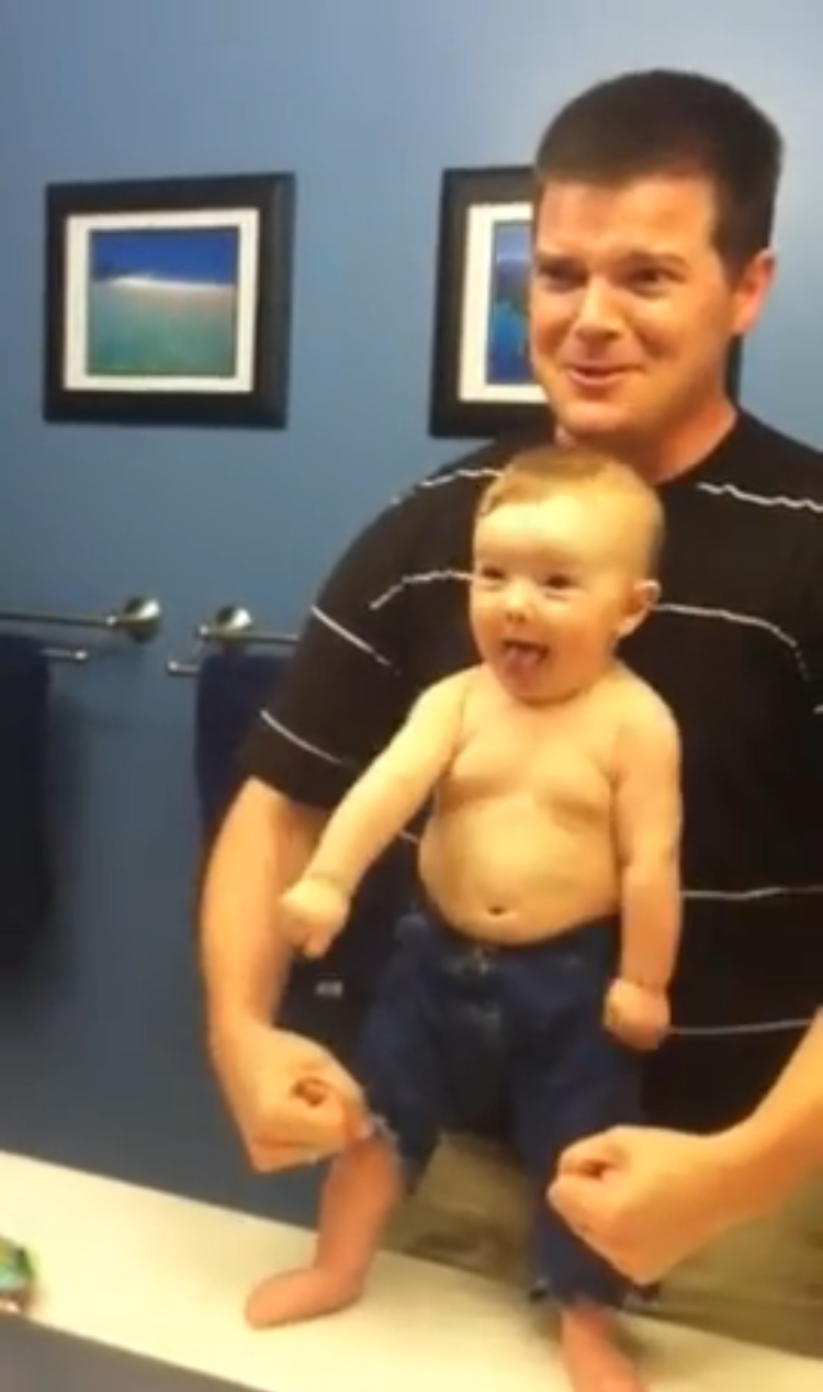 Strong baby flexes muscles making dad fall apart with laughter