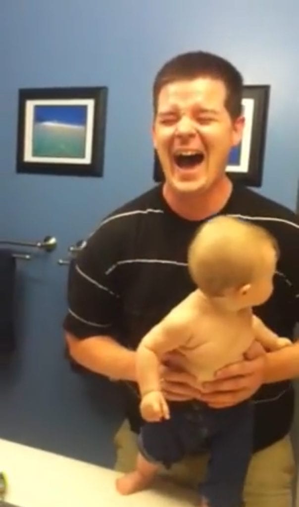 Strong baby flexes muscles making dad fall apart with laughter